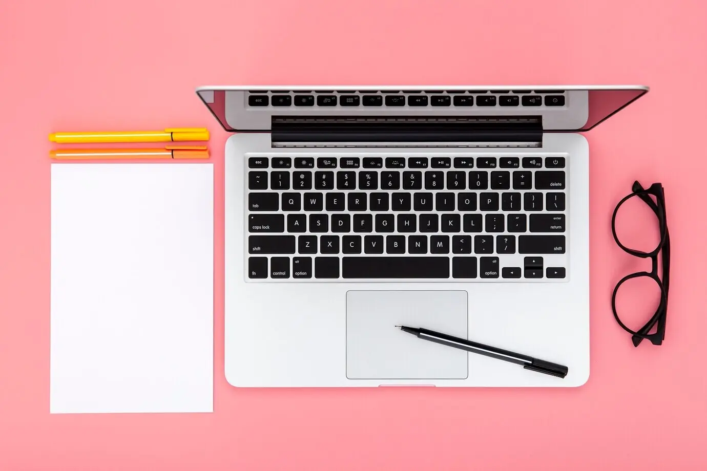 Anordnung von Schreibtischgegenständen auf pinkem Hintergrund
